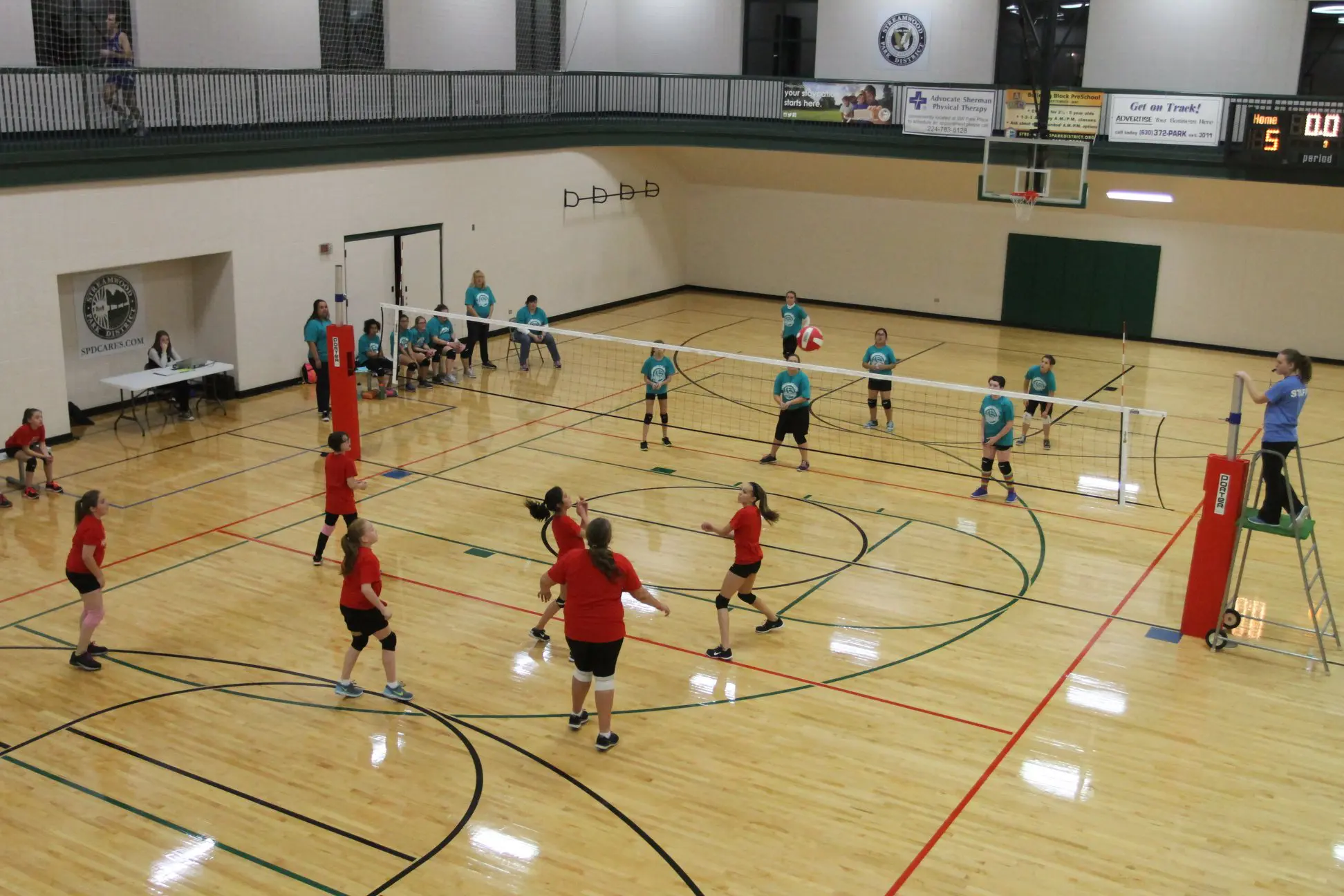 a group of people playing volleyball in a gym