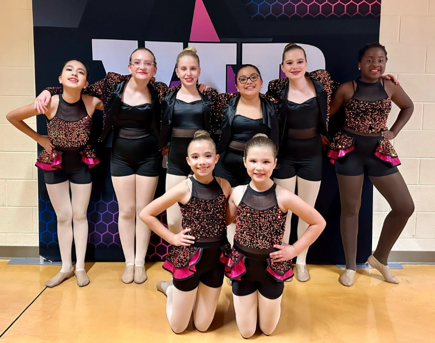 a group of childs in black and pink cheer uniforms posing for a photo