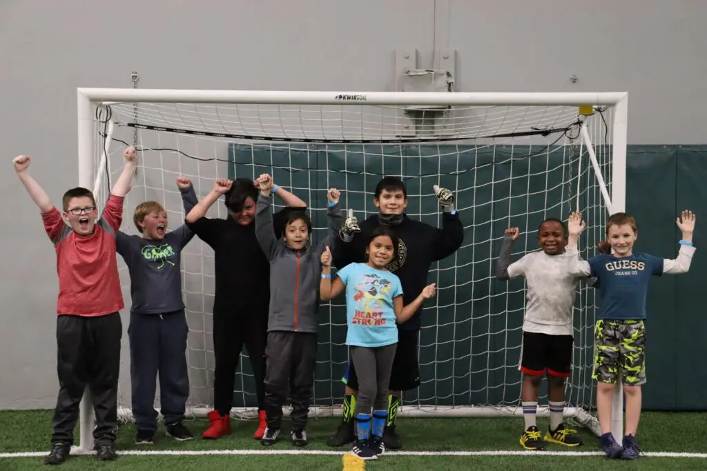 a group of kids standing in front of a goal