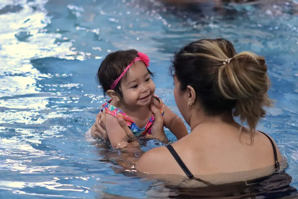 a person holding a baby in a pool
