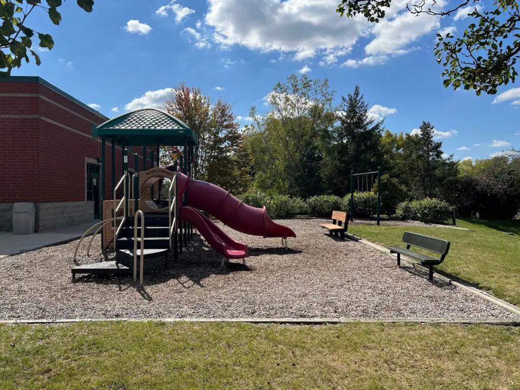 a playground with a red slide and benches