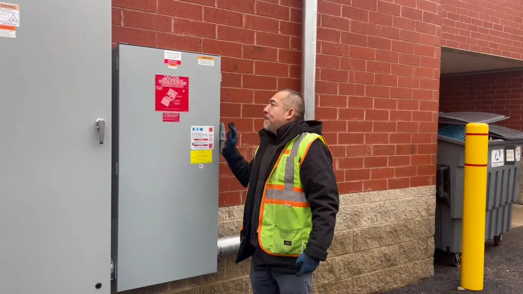 a person in a safety vest and gloves looking at a box