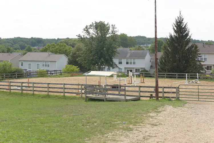 a horse arena with a fence and a house