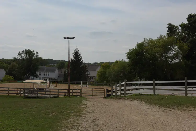 a dirt road with a fence and a fenced in area