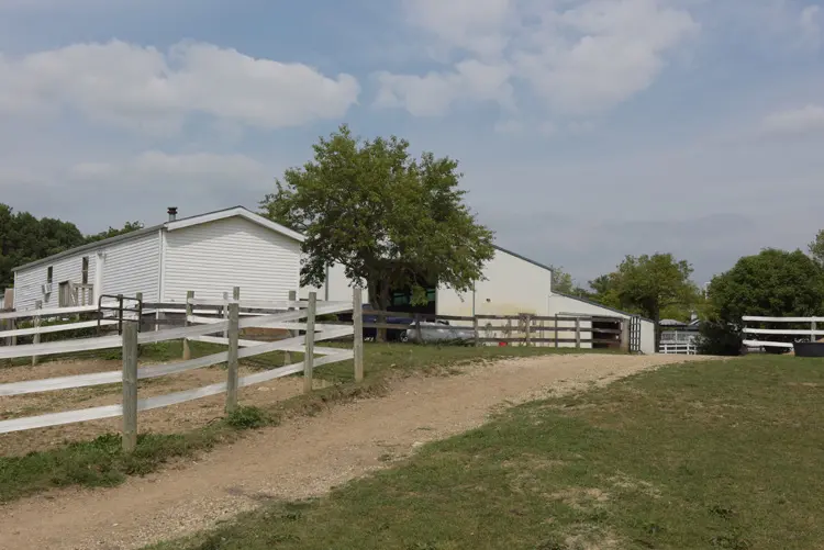 a dirt road leading to a white building