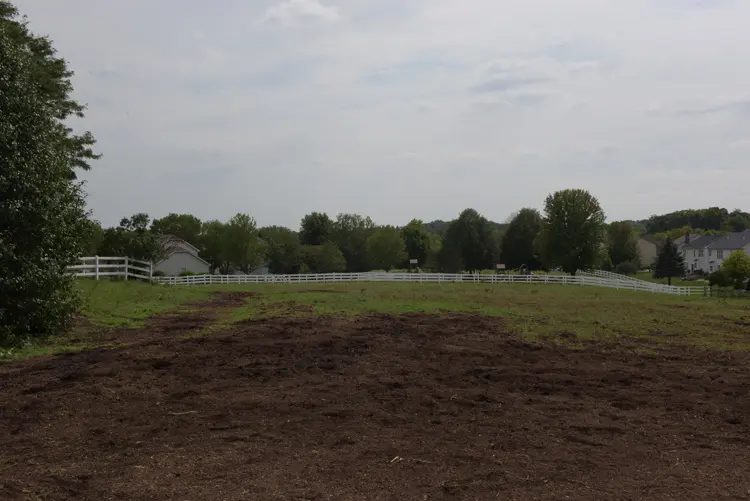 a field with a white fence and a house