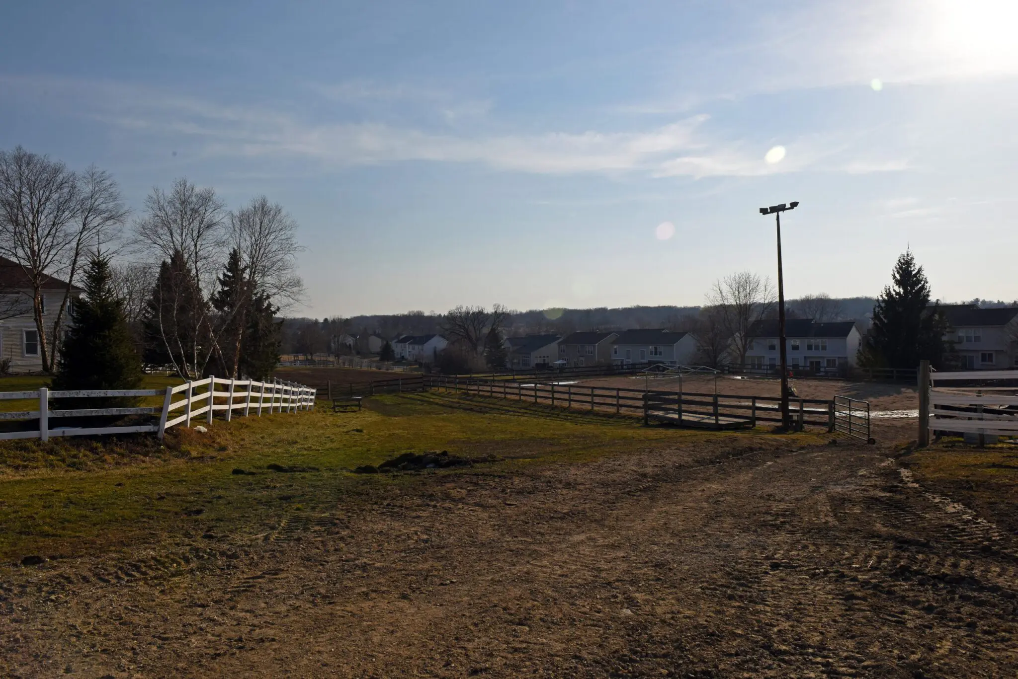a fenced in field with houses and trees