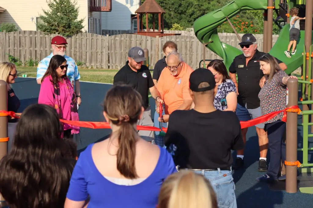 a group of people cutting a red ribbon