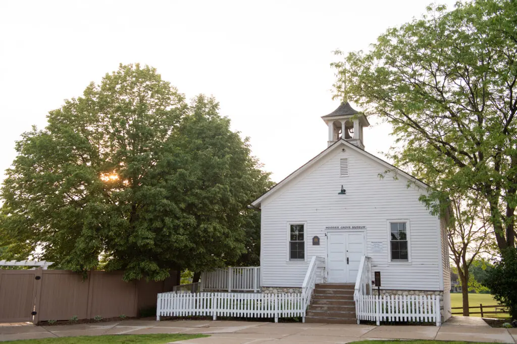 a white building with a bell tower and a white picket fence