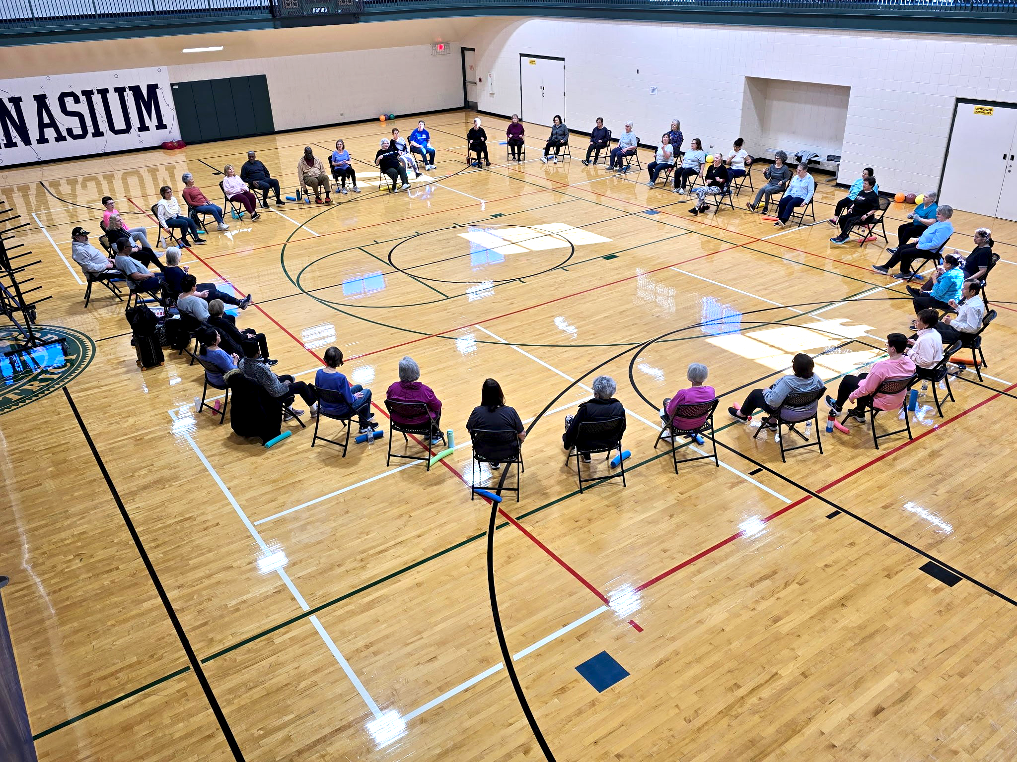 a group of people sitting in chairs in a gym