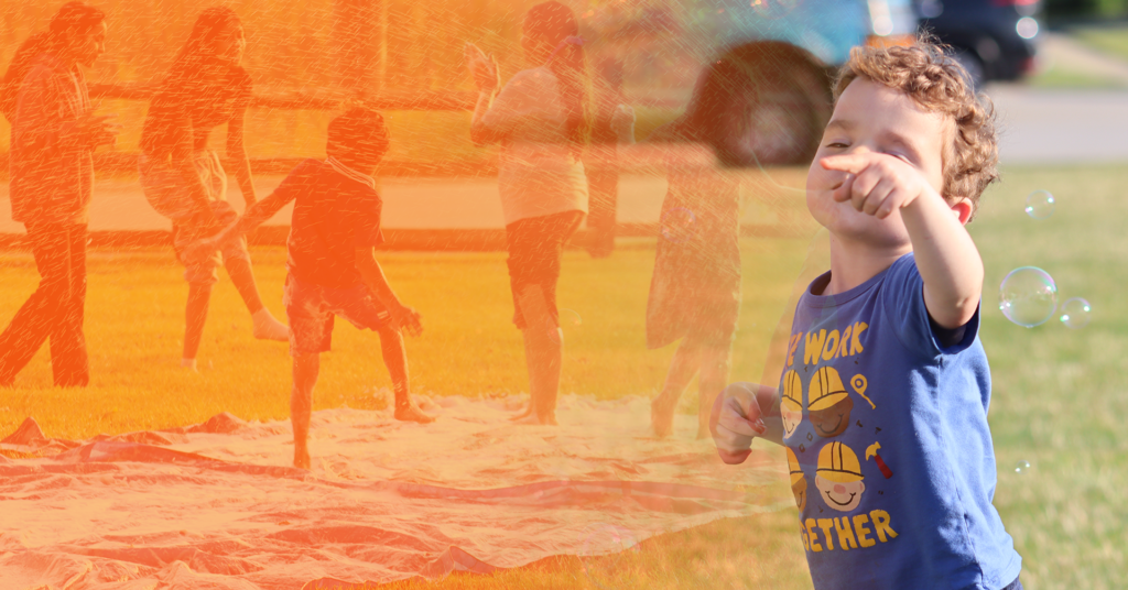 a child standing on a blanket with other people in the background
