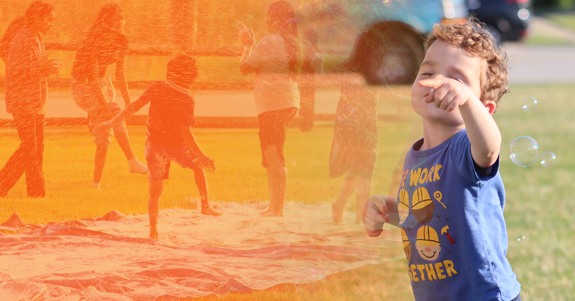 a child standing on a blanket with other people in the background