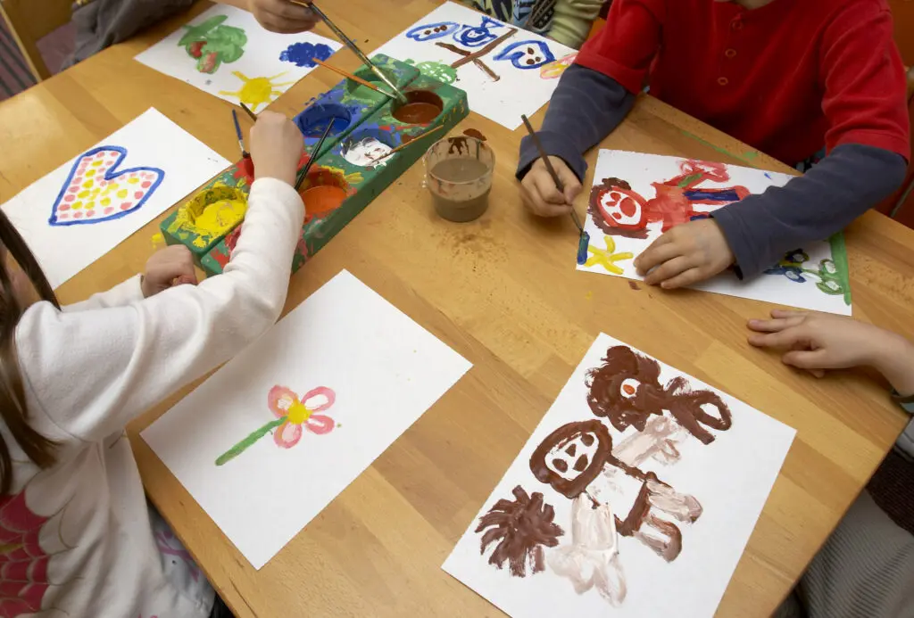 a group of children painting on paper